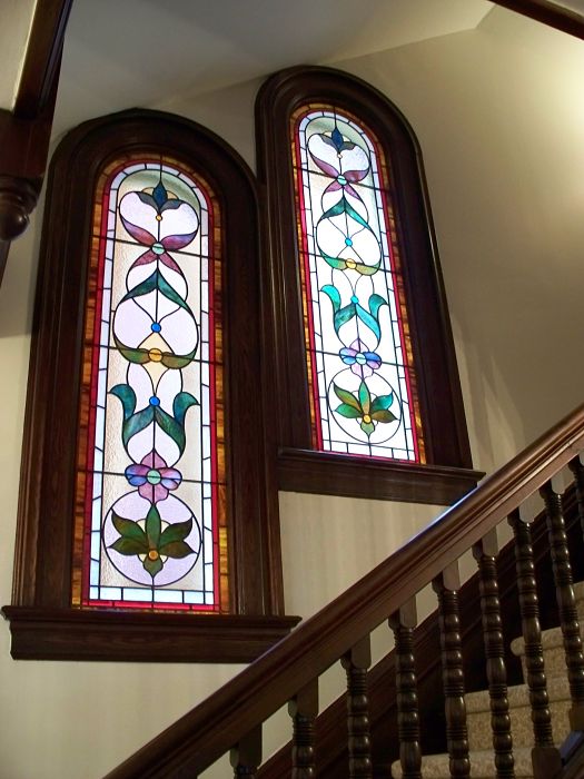 Two stained glass Victorian windows on a stairway